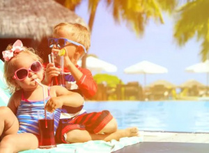 dziewczynka i chłopiec siedzce na leżaku na tle basenu